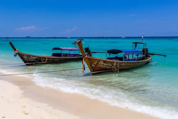 Koh Phi Phi, Tayland - 7 Mayıs 2018: Duru turkuaz suları ile kumlu bir plaj üzerinde uzun kuyruk yerel tekneler demirli