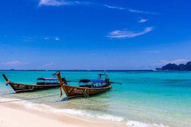 Koh Phi Phi, Tayland - 7 Mayıs 2018: Duru turkuaz suları ile kumlu bir plaj üzerinde uzun kuyruk yerel tekneler demirli