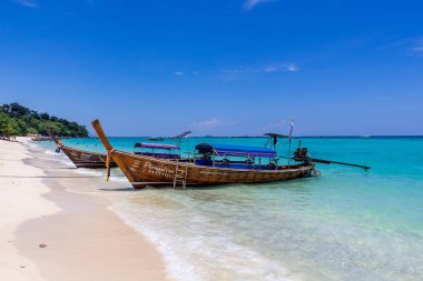 Koh Phi Phi, Tayland - 7 Mayıs 2018: Duru turkuaz suları ile kumlu bir plaj üzerinde uzun kuyruk yerel tekneler demirli
