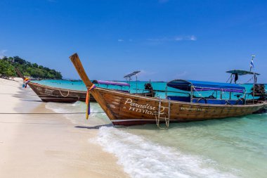 Koh Phi Phi, Tayland - 7 Mayıs 2018: Duru turkuaz suları ile kumlu bir plaj üzerinde uzun kuyruk yerel tekneler demirli