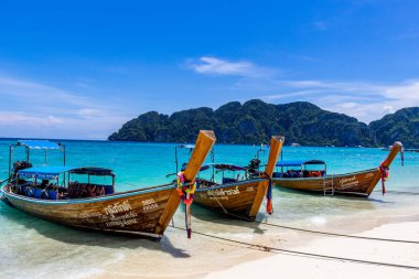 Koh Phi Phi, Tayland - 7 Mayıs 2018: Duru turkuaz suları ile kumlu bir plaj üzerinde uzun kuyruk yerel tekneler demirli