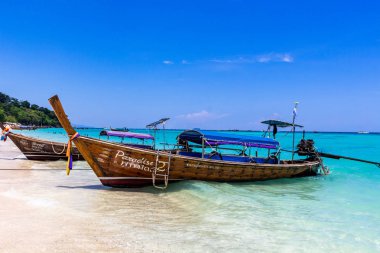 Koh Phi Phi, Tayland - 7 Mayıs 2018: Duru turkuaz suları ile kumlu bir plaj üzerinde uzun kuyruk yerel tekneler demirli