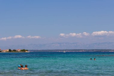 Zadar, Hırvatistan - 24 Temmuz 2018: Ugljan Island şeffaf sularda yüzme insanlar