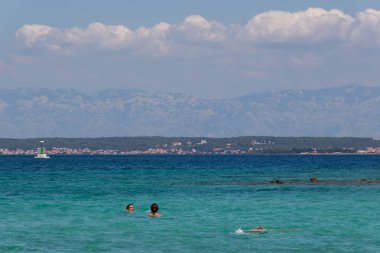 Zadar, Hırvatistan - 24 Temmuz 2018: Ugljan Island şeffaf sularda yüzme insanlar