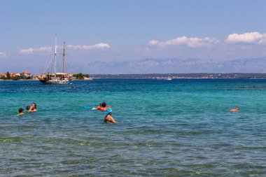 Zadar, Hırvatistan - 24 Temmuz 2018: Ugljan Island şeffaf sularda yüzme insanlar