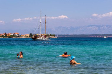 Zadar, Hırvatistan - 24 Temmuz 2018: Ugljan Island şeffaf sularda yüzme insanlar