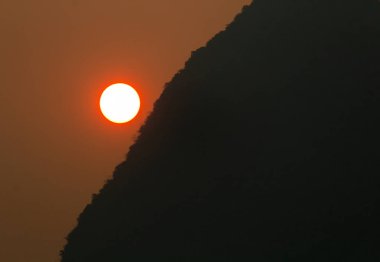 Sezon içinde Kuzey Laos yanma sırasında kırmızı günbatımı sisli kalker tepe üzerinde