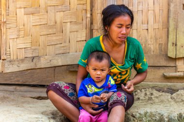 bachong Nay,, Laos - 10 Nisan 2018: anne ve Laos bir uzak köy bambu evin önünde oturan bir etnik azınlık kızgın çocuk