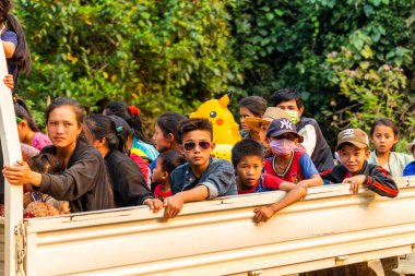 Muang Ngoi, Laos - 10 Nisan 2018: Laos iki uzak köy arasında bir nehir üzerinde taşıma yolcu ve okul çocukları kamyon