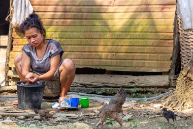 Bachong Nay,, Laos - 10 Nisan 2018: Laos bir uzak köy tavuk çevrili kendi bambu evin önünde el yıkama yapıyor yerel kadın