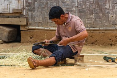 Muang Ngoi, Laos - 10 Nisan 2018: Laos uzak bir bölgede kırsal onun evinin önünde bir bambu kesme yerel adam