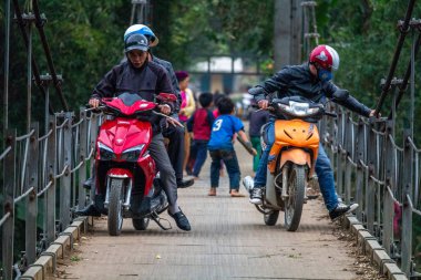 Ha Giang, Vietnam - 17 Mart 2018: motosiklet ve Kuzey Vietnam orman çevrili bir metal köprüyü geçtikten çocuk