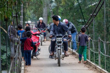 Ha Giang, Vietnam - 17 Mart 2018: motosiklet ve Kuzey Vietnam orman çevrili bir metal köprüyü geçtikten çocuk