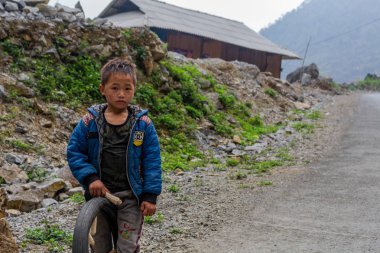 Ha Giang, Vietnam - 17 Mart 2018: Kuzey Vietnam uzak bir dağlık alanda bir lastik ile oynarken Hmong etnik azınlık çocuktan
