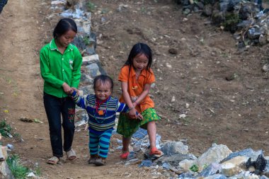 Ha Giang, Vietnam - 17 Mart 2018: Kuzey Vietnam dağlarında bir köyde asfalt bir yolda yürürken Hmong etnik azınlık çocuk
