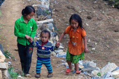 Ha Giang, Vietnam - 17 Mart 2018: Kuzey Vietnam dağlarında bir köyde asfalt bir yolda yürürken Hmong etnik azınlık çocuk