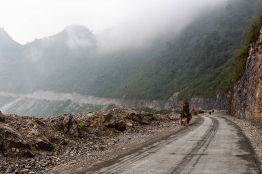 Ha Giang, Vietnam - 17 Mart 2018: Kuzey Vietnam dağlarında bir yolda bitkilerin büyük yükler taşıyan kadın tarım işçileri