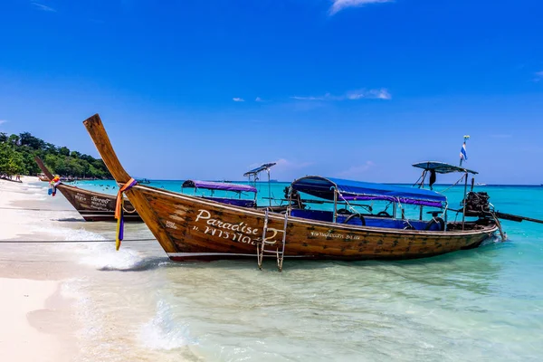 Koh Phi Phi, Tayland - 7 Mayıs 2018: Duru turkuaz suları ile kumlu bir plaj üzerinde uzun kuyruk yerel tekneler demirli
