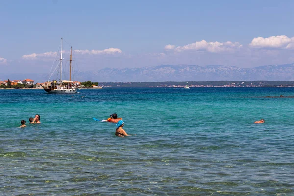 Zadar, Hırvatistan - 24 Temmuz 2018: Ugljan Island şeffaf sularda yüzme insanlar
