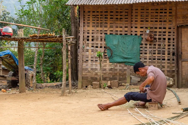 Muang Ngoi, Laos - 10 Nisan 2018: Laos uzak bir bölgede kırsal onun evinin önünde bir bambu kesme yerel adam