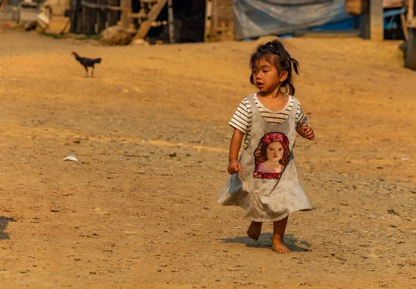 Ban Na, Laos - 10 Nisan 2018: yalnız Kuzey Laos uzak bir köyde tozlu döşemeli yolun üzerinde yürüyen etnik azınlık çocuk