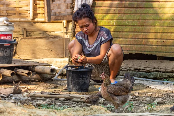 Bachong Nay,, Laos - 10 Nisan 2018: Laos bir uzak köy tavuk çevrili kendi bambu evin önünde el yıkama yapıyor yerel kadın
