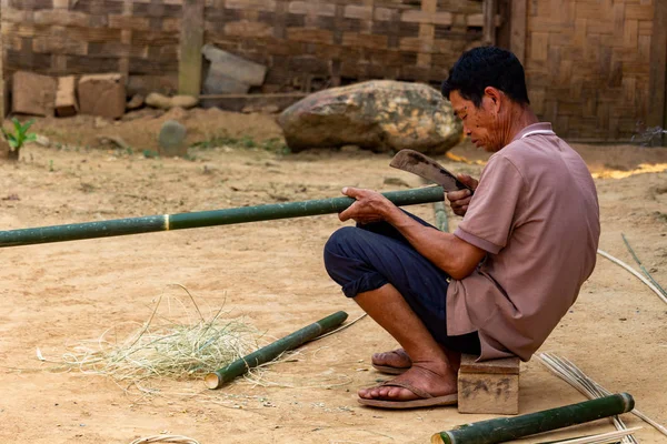 Ban Na, Laos - 10 Nisan 2018: ahşap evinin önünde bir bambu kesme etnik azınlık köylü