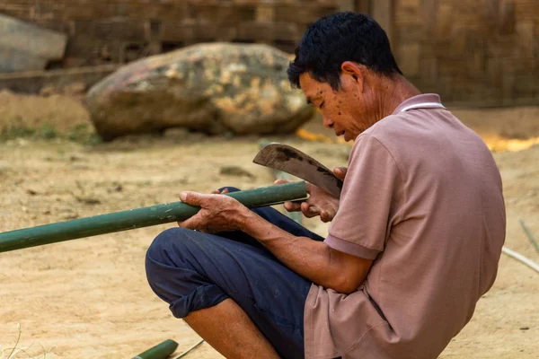 Ban Na, Laos - 10 Nisan 2018: ahşap evinin önünde bir bambu kesme etnik azınlık köylü