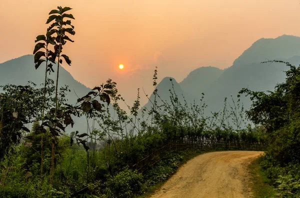 老挝芒爱民 2018年4月10日 在老挝北部农村铺设的道路在燃烧季节被大雾笼罩的山脉包围着 — 图库照片