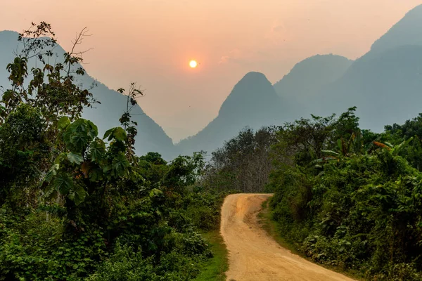 老挝芒爱民 2018年4月10日 在老挝北部农村铺设的道路在燃烧季节被大雾笼罩的山脉包围着 — 图库照片
