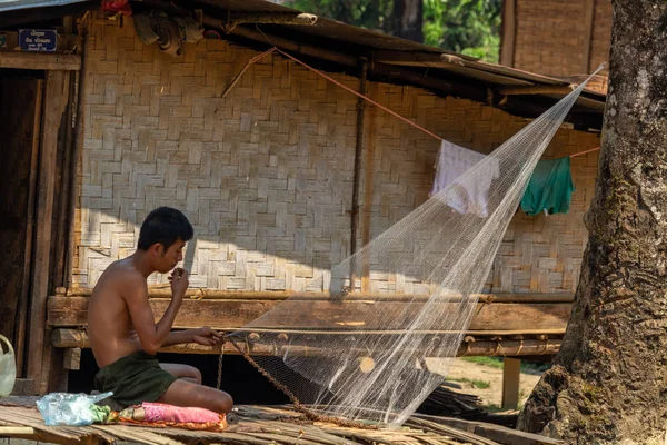 Bachong Nay,, Laos - 10 Nisan 2018: kendi bambu evin önünde bir net tamir bir etnik azınlık Köyü ile ilgili yerel adam