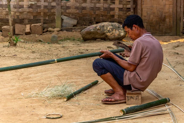 Ban Na, Laos - 10 Nisan 2018: ahşap evinin önünde bir bambu kesme etnik azınlık köylü