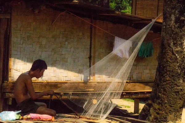 Bachong Nay,, Laos - 10 Nisan 2018: kendi bambu evin önünde bir net tamir bir etnik azınlık Köyü ile ilgili yerel adam
