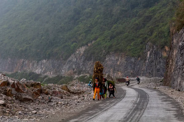 Ha Giang, Vietnam - 17 Mart 2018: Kuzey Vietnam dağlarında bir yolda bitkilerin büyük yükler taşıyan kadın tarım işçileri