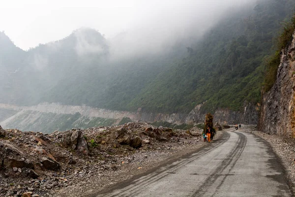 Ha Giang, Vietnam - 17 Mart 2018: Kuzey Vietnam dağlarında bir yolda bitkilerin büyük yükler taşıyan kadın tarım işçileri