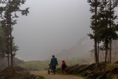 Ha Giang, Vietnam - 17 Mart 2018: baba ve çocuk Kuzey Vietnam sisli karstik dağlarında bir tarım aracı ile