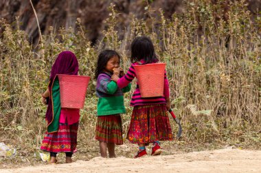 Ha Giang, Vietnam - March 18, 2018: Children with agricultural baskets playing in the mountains of northern Vietnam bordering with China clipart