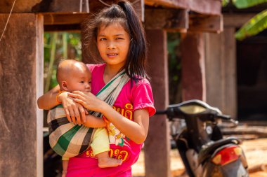 Thakhek, Laos - 20 Nisan 2018: Genç bir çocuk tutarak ve Güney Laos'ta poz anne. Güneydoğu Asya'da annelik normalde erken yaşta yer alır