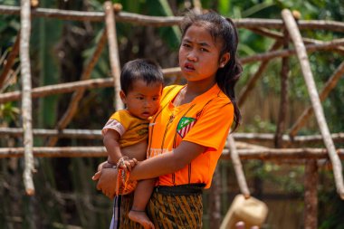 Thakhek, Laos - 20 Nisan 2018: Genç bir çocuk tutarak ve Güney Laos'ta poz anne. Güneydoğu Asya'da annelik normalde erken yaşta yer alır