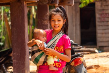 Thakhek, Laos - 20 Nisan 2018: Genç bir çocuk tutarak ve Güney Laos'ta poz anne. Güneydoğu Asya'da annelik normalde erken yaşta yer alır