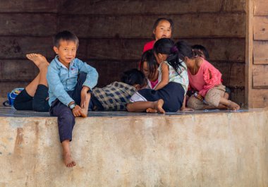 Thakhek, Laos - 20 Nisan 2018: rahatlatıcı ve Güney Laos uzak bir kırsal kasabada bir evin önünde oynayan çocuklar