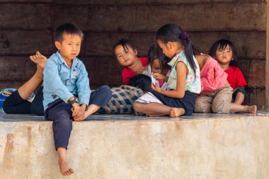 Thakhek, Laos - 20 Nisan 2018: rahatlatıcı ve Güney Laos uzak bir kırsal kasabada bir evin önünde oynayan çocuklar