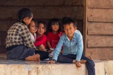 Thakhek, Laos - 20 Nisan 2018: rahatlatıcı ve Güney Laos uzak bir kırsal kasabada bir evin önünde oynayan çocuklar