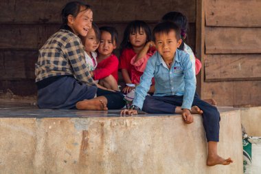 Thakhek, Laos - 20 Nisan 2018: rahatlatıcı ve Güney Laos uzak bir kırsal kasabada bir evin önünde oynayan çocuklar