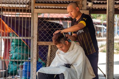 Thakhek, Laos - 20 Nisan 2018: Güney Laos uzak bir kırsal kasabada yerel bir sokak Kuaför, bir saç kesimi olan adam