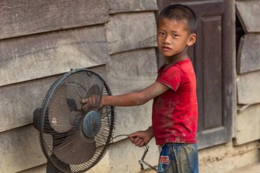 Thakhek, Laos - 20 Nisan 2018: solunum Güney Laos uzak bir kırsal kasabada bir ahşap evin önünde dokunmadan etnik azınlık çocuk