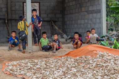 Thakhek, Laos - 20 Nisan 2018: Yerel erkek birlikte Güney Laos uzak bir kırsal kasabada bir evin önünde oturan Grup