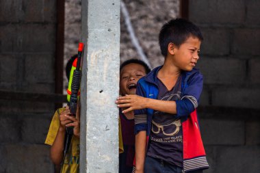 Thakhek, Laos - 20 Nisan 2018: Grup Güney Laos uzak bir zavallı alanda plastik silahla oynarken çocuk