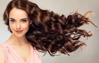 Uzun, sağlıklı ve parlak kıvırcık saçlı esmer kız. Güzel model kadınla dalgalı saç modeli. Bakım ve güzellik