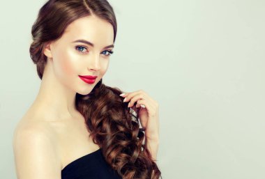 Kıvırcık Kahverengi saçlı güzel model kızı. Dalgalı saç modeli olan esmer kadın. Kırmızı dudaklar, elbise ve manikür çivi. Moda, güzellik ve portre makyaj